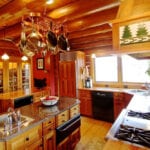 A kitchen with wooden cabinets and floors, stove top oven.