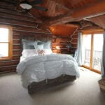 A bedroom with a bed, ceiling fan and windows.