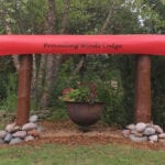 A red pole with rocks around it and a flower pot.